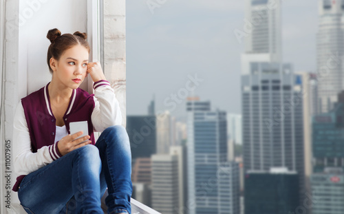 Photography teenage girl sitting on windowsill with smartphone