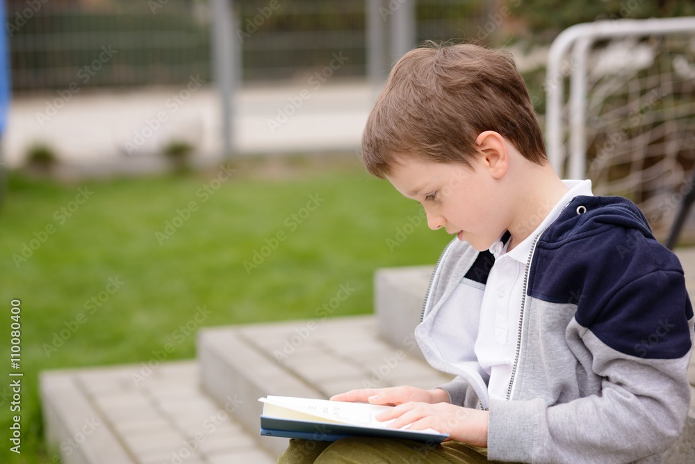 7 year old boy reading a book on the terrace 7 year old boy reading a book on the terrace