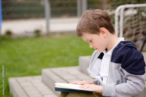 7 year old boy reading a book on the terrace