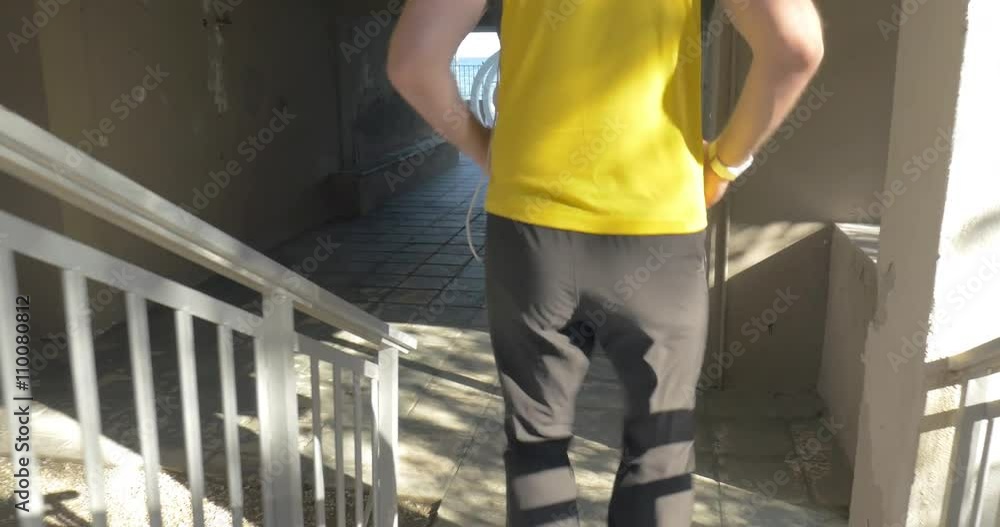 Young man in headphones is running down the stairs of his house, opening the gates and starting his morning jogging. Young man in headphones is running down the stairs of his house, opening the gates and starting his morning jogging.