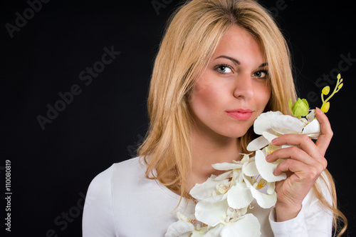 Portrait of a nice girl with a white orchid on a black background