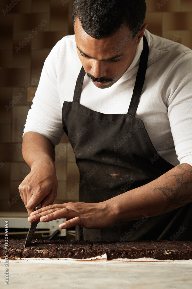 Serious professional black baker cut piece of homemade organic