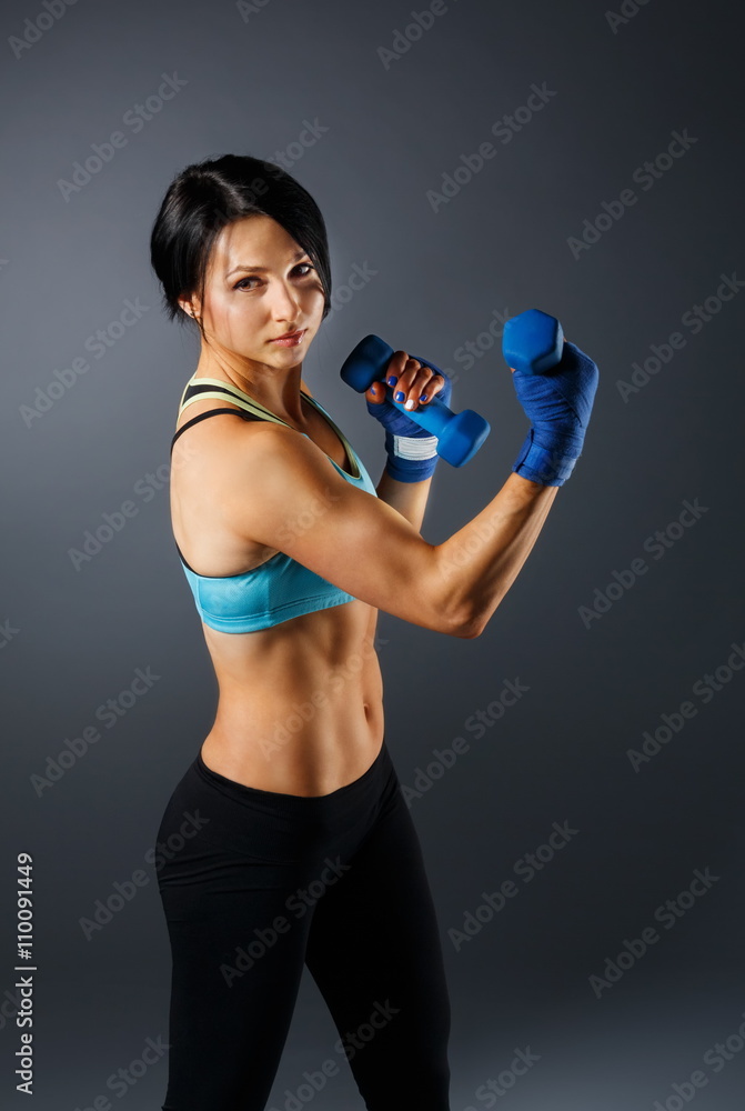 Young sportive woman with dumbbells at grey background Young sportive woman with dumbbells at grey background
