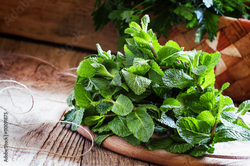 Fresh peppermint and other herbs, wood background, country style