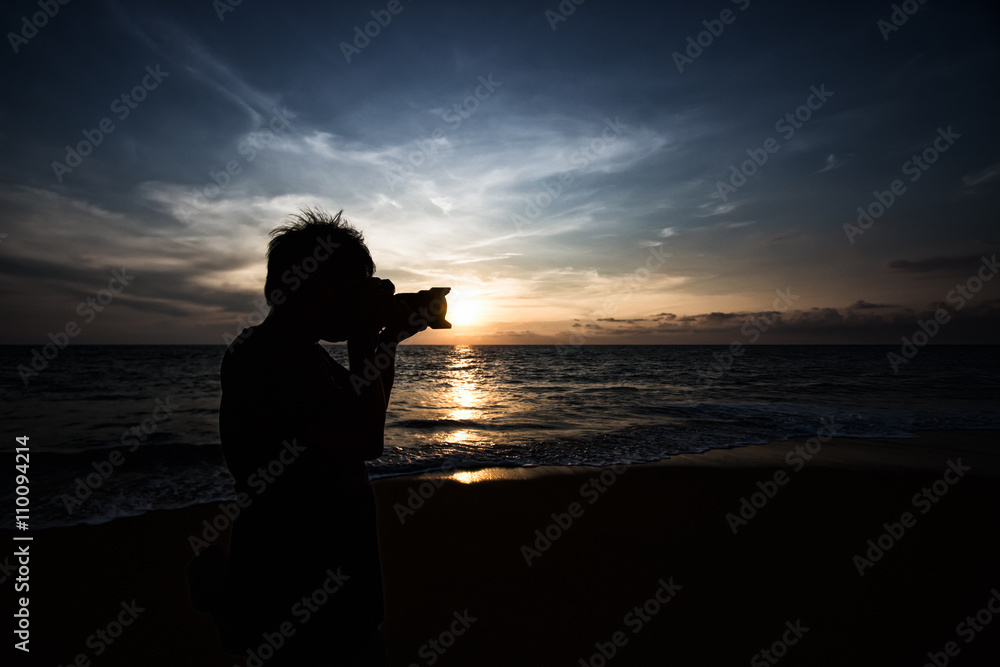 Silhouette of photographer taking photo on the beach before suns