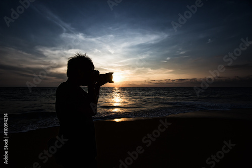 Silhouette of photographer taking photo on the beach before suns