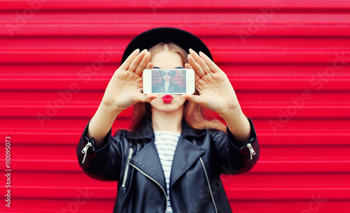 Fashion glamour woman makes self portrait on smartphone blowing photo