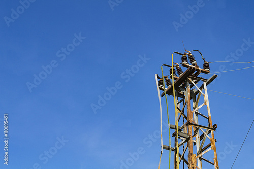 The top of a rusty metal pole with insulators for electric wires photo