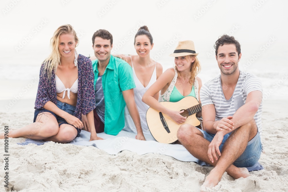 Group of friends sitting on the beach with guitar Group of friends sitting on the beach with guitar