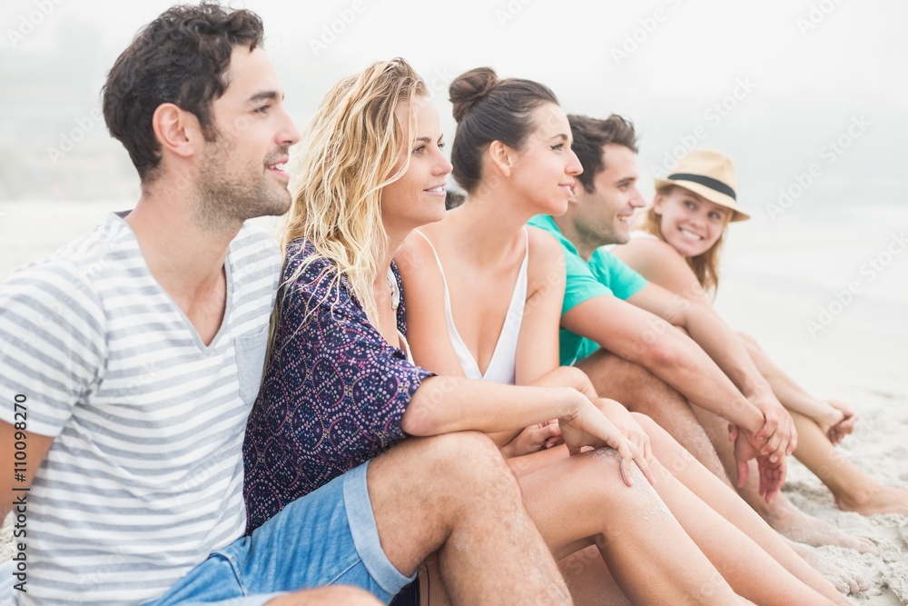 Group of friends sitting side by side on the beach Group of friends sitting side by side on the beach