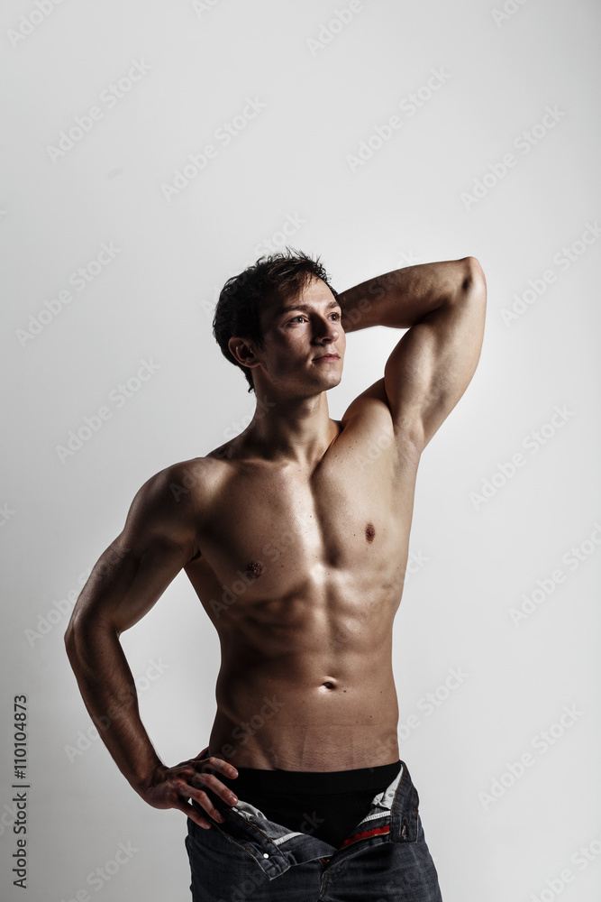 Muscular male model bodybuilder with unbuttoned jeans. Studio shot on gray background. Fitness MODEL. Great for commercial. Ideal fitness body with six pack, perfect abs, shoulders. Muscular male model bodybuilder with unbuttoned jeans. Studio shot on gray background. Fitness MODEL. Great for commercial. Ideal fitness body with six pack, perfect abs, shoulders.