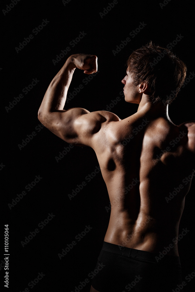 Muscular BACK of male model bodybuilder preparing for fitness training, turned back. Studio shot on black background. Black and white photo. Perfect fitness body. Ideal for commercial.