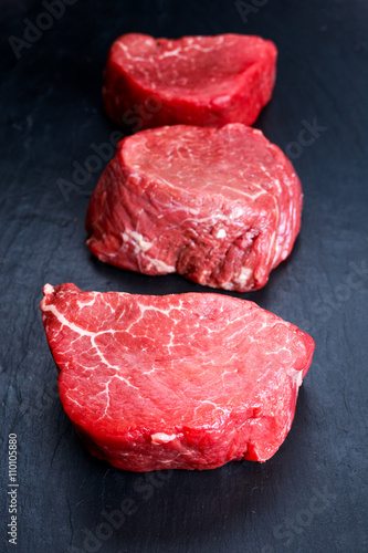 Fresh Raw Beef steak Mignon on blue dark board background. 