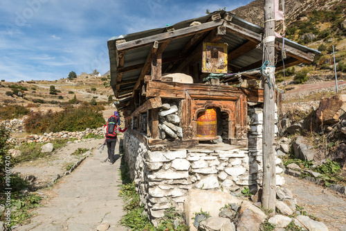 Trekker passing buddhist praying wheels.