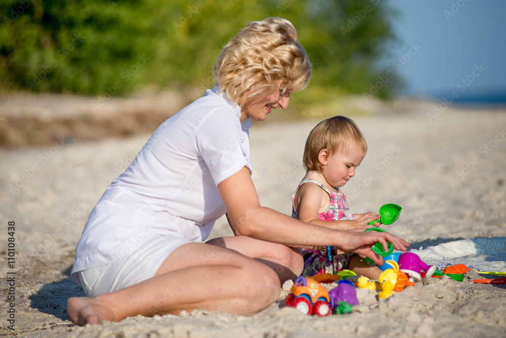 Mama with a daughter playing on the beach Mama with a daughter playing on the beach