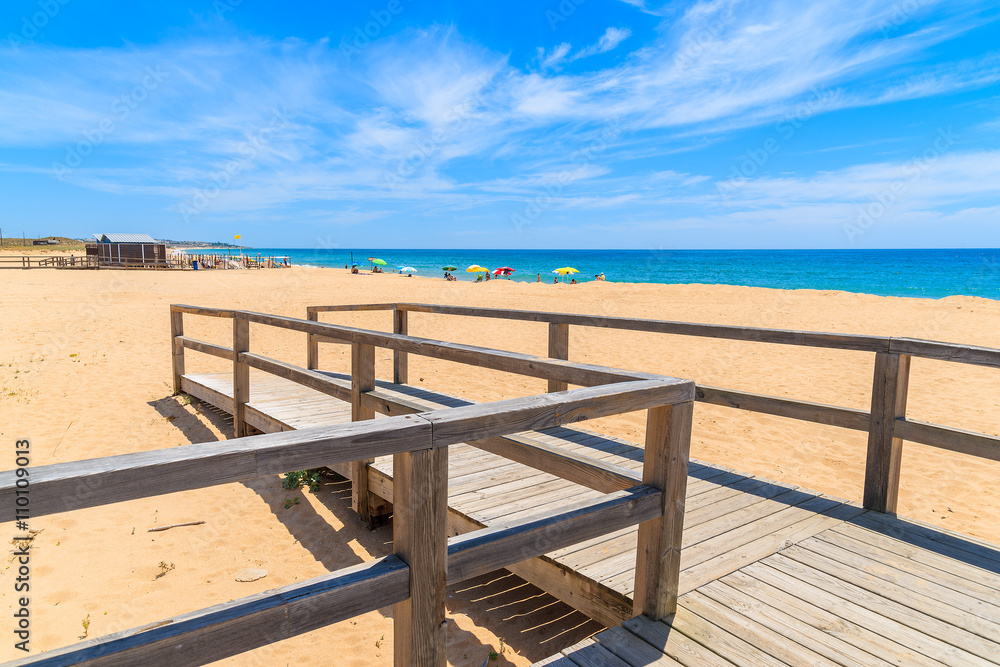 Wooden footbridge to sandy beach in Armacao de Pera coastal town, Algarve region, Portugal