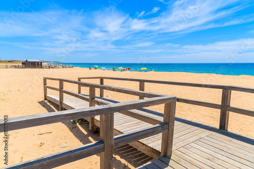 Tablou canvas Wooden footbridge to sandy beach in Armacao de Pera coastal town, Algarve region
