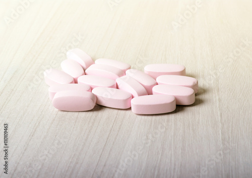 Pink probiotic pills or vitamins on a wooden background.