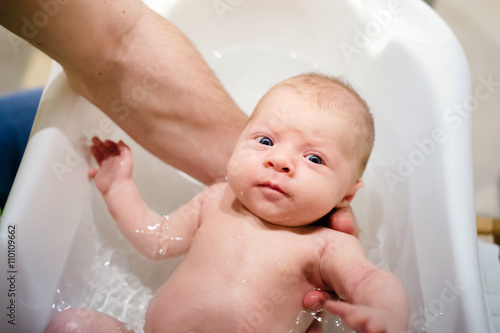 Unrecognizable young father bathing his little baby son