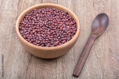Bowl with beans and wooden spoon on a wooden background