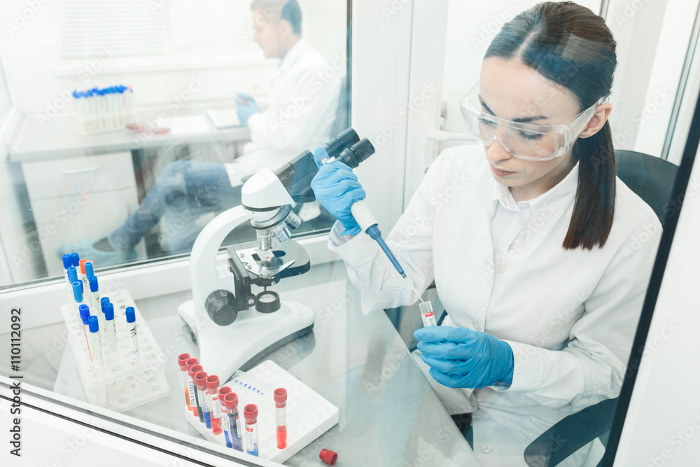 Skillful young scientists examining virus in laboratory Skillful young scientists examining virus in laboratory