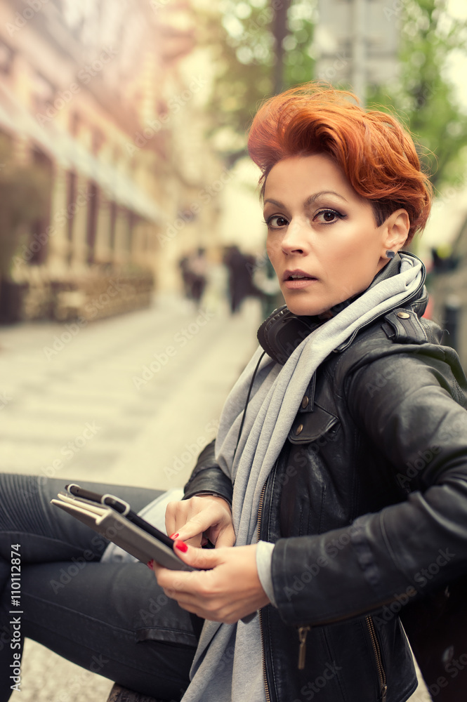 Young woman on a street bench with tablet computer / Young beautiful woman sitting on a bench on the street with tablet computer Young woman on a street bench with tablet computer / Young beautiful woman sitting on a bench on the street with tablet computer