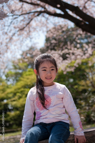 桜の木の前で笑う日本人の女の子
