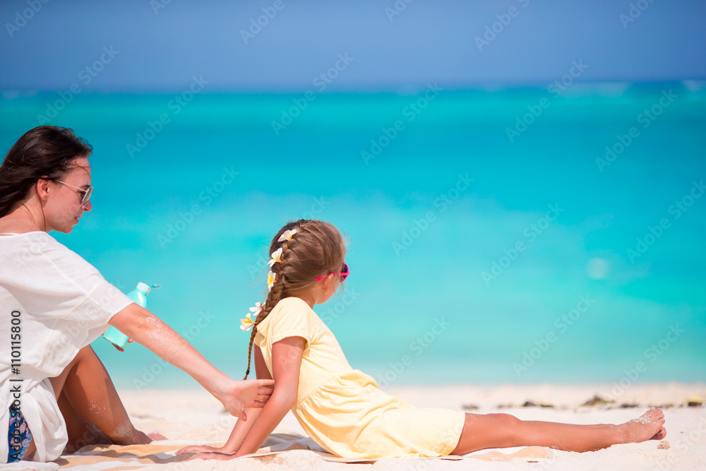 Fototapeta premium Mother applying sun protection cream to her daughter at tropical beach