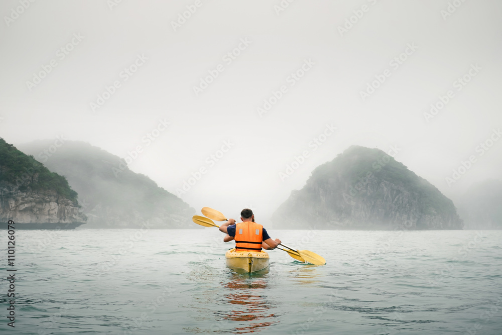 Couple paddling the kayak in mist weather - obrazy, fototapety, plakaty 