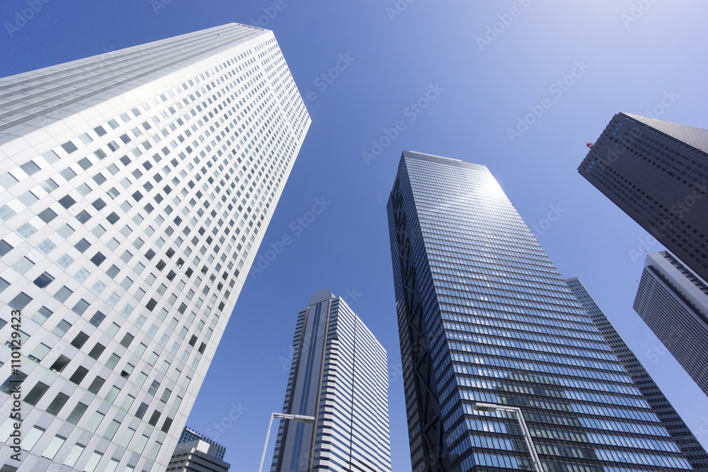 新宿高層ビル街快晴　青空　超広角で見上げる　コピースペース　ビルに反射する太陽