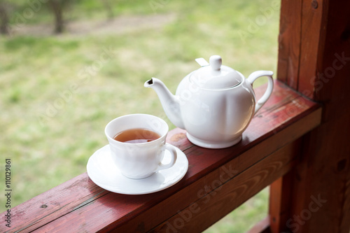 Cup of black tea and kettle on veranda