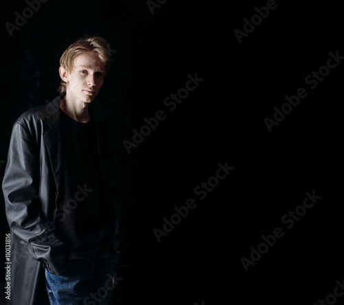 Dark studio fashion portrait of young serious elegant man. Black background for text