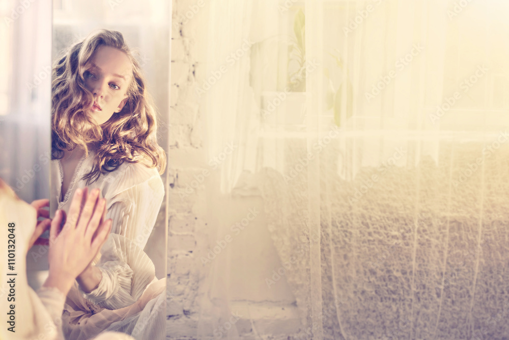 Fototapeta premium portrait of elegance young woman in white dress looking to the mirror reflection