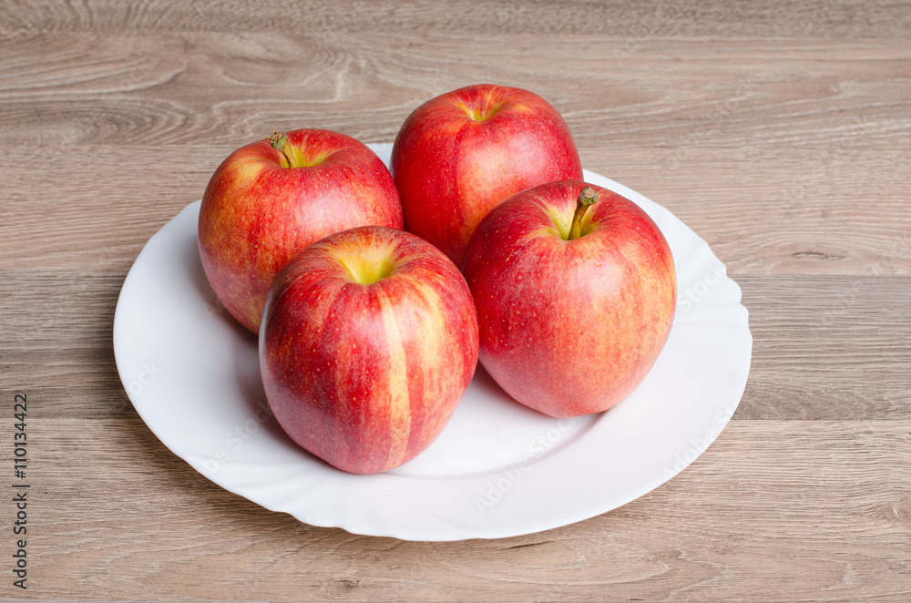 Red apples on white plate and wood table Red apples on white plate and wood table