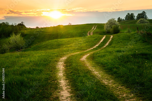 Fototapeta Naklejka Na Ścianę i Meble -  The Sun set over the dirt, winding road. May 2016, Masuria, Poland.
