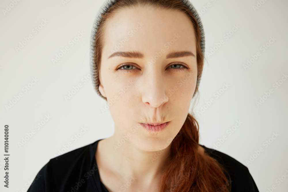 Close up portrait of skeptical young woman looking suspicious, with disgusted expression on her face, mixed with disapproval, isolated against white background. Negative human emotions, and feelings Close up portrait of skeptical young woman looking suspicious, with disgusted expression on her face, mixed with disapproval, isolated against white background. Negative human emotions, and feelings