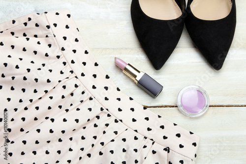 black female shoes with a skirt and lipstick with powder on white wooden background