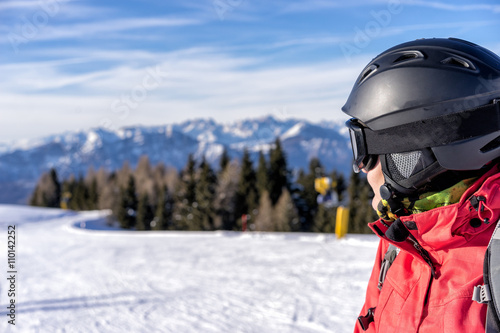 Female skier enjoys view on italien slopes with beautiful mountains in distance. Head detail.