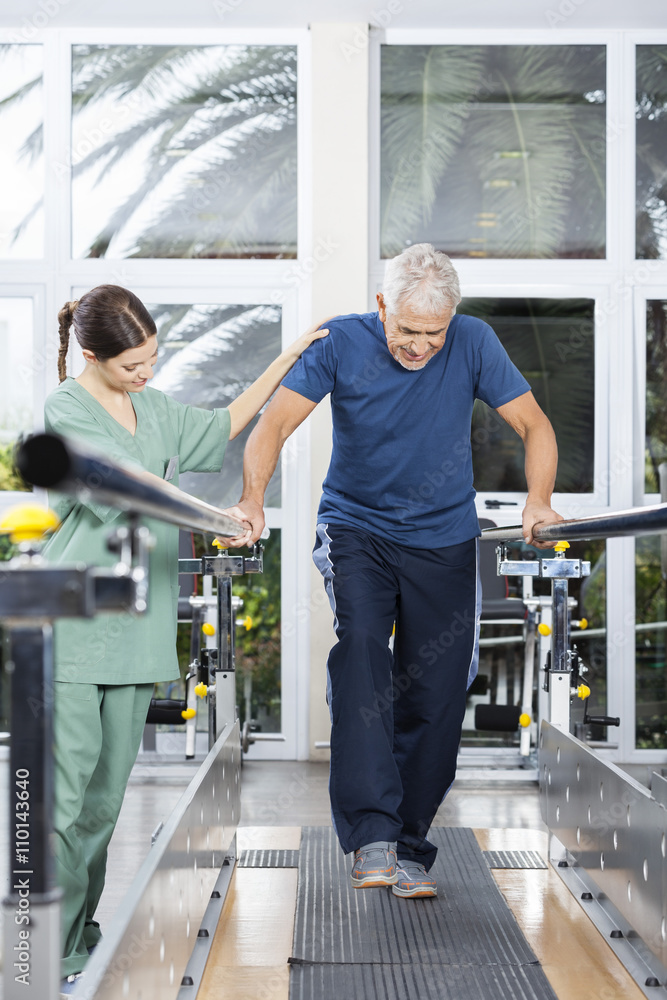 Female Physiotherapist Motivating Senior Man To Walk In Rehab Ce