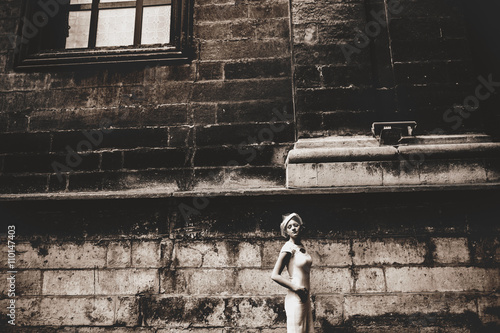 Photography A thin lady in a hat with a veil stand in the front of old stone