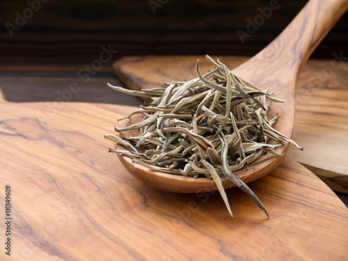 Silver tips white tea in the olive tree wooden spoon photo