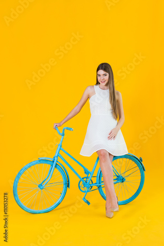 Fototapeta Naklejka Na Ścianę i Meble -  Beautiful young woman posing seated on a blue bicycle