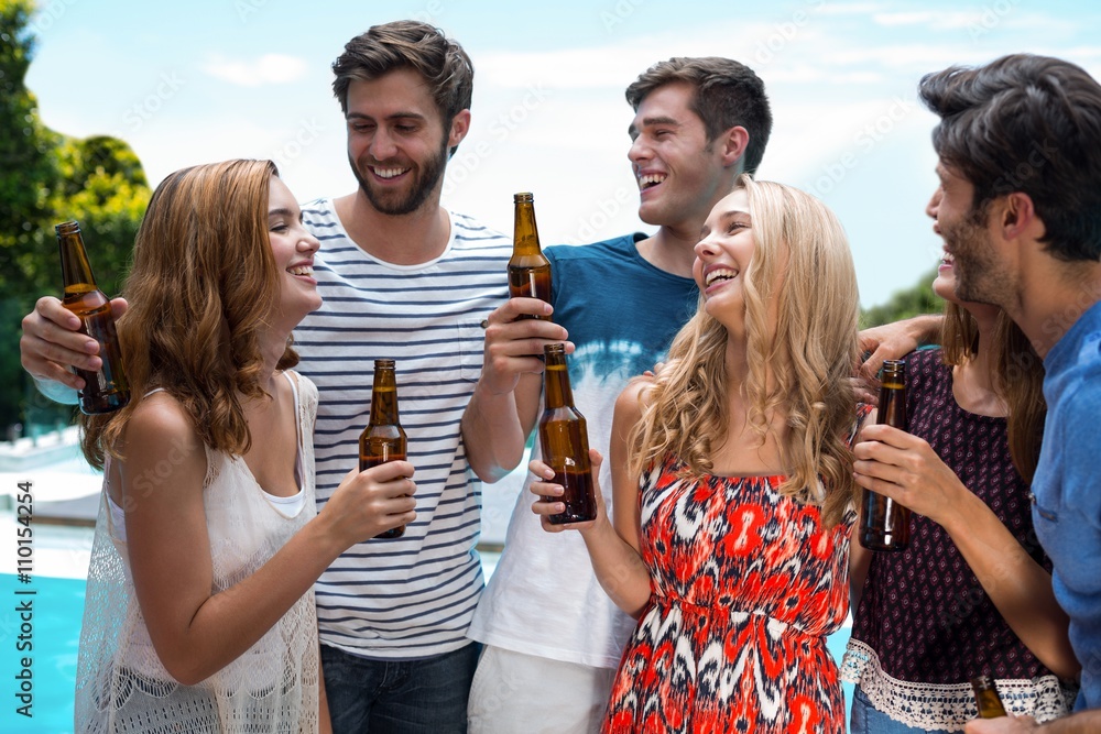Group of happy friend holding beer bottles near pool