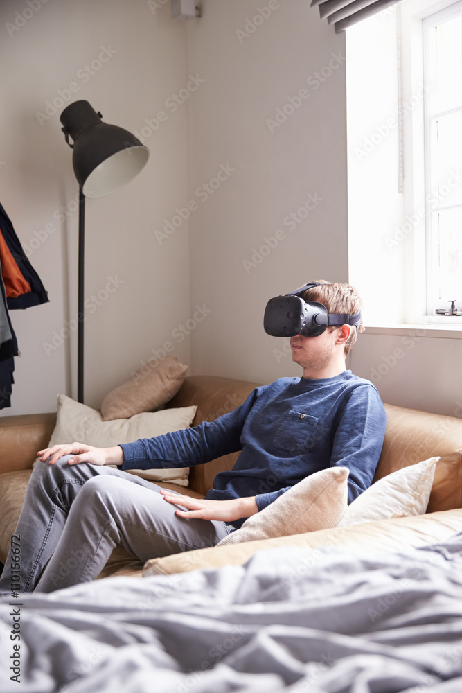 Fototapeta premium Man Sitting On Sofa At Home Wearing Virtual Reality Headset