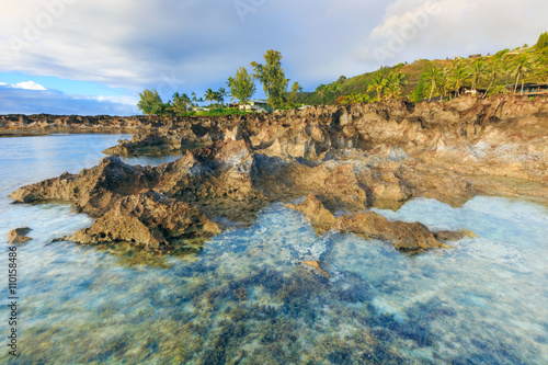 The lava coast of the Pacific ocean. North shore Oahu island, Hawaii. Sharp lava rock formations at low tide.