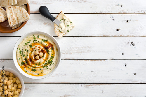 Foto Hummus in bowl on white wooden table