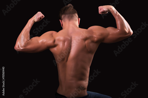 attractive bodybuilder sportsman shows perfect body muscles on black background; fitness man; bodybuilding and gym sport; athlete guy;