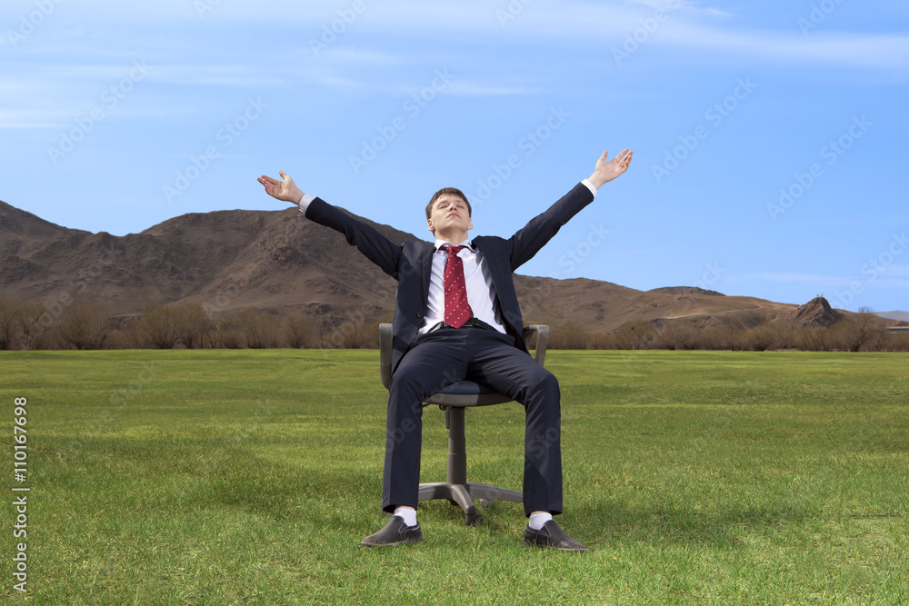 Businessman sitting on chair on green meadow Businessman sitting on chair on green meadow