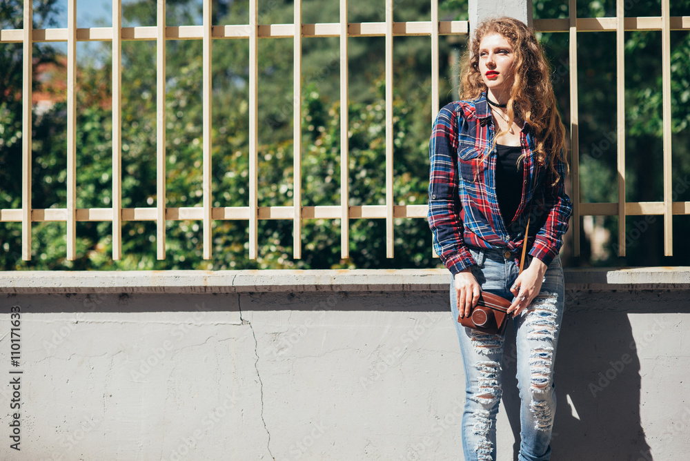 Beautiful woman with long blond curly hair in urban background with vintage camera Beautiful woman with long blond curly hair in urban background with vintage camera