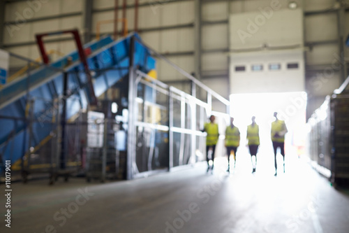 Four figures walking in an industrial interior, soft focus photo